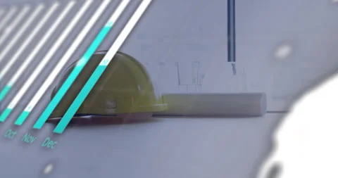 Yellow hard hat resting beside rolled blueprint on desk, showing bar chart Stock-Footage 307435297