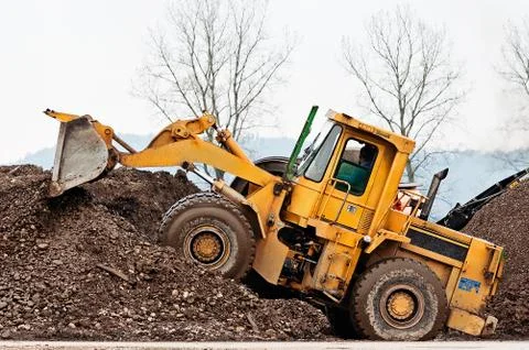 Yellow heavy wheel loader piling dirt at rock and dirt separation site Stock Photos