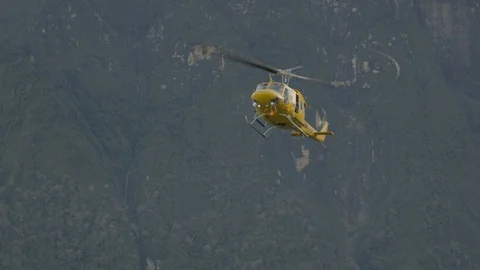 Yellow hellicopter is about to land in the mountains Stock Footage 121667025