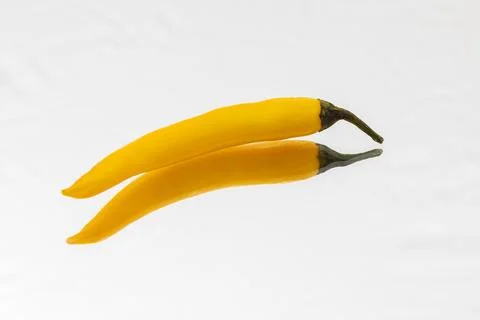 Yellow hot pepperoni is reflected on a white table. Foto stock