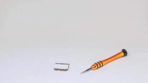 Yellow hour screwdriver and computer chip lie on a white background. Isolated Stock Photos