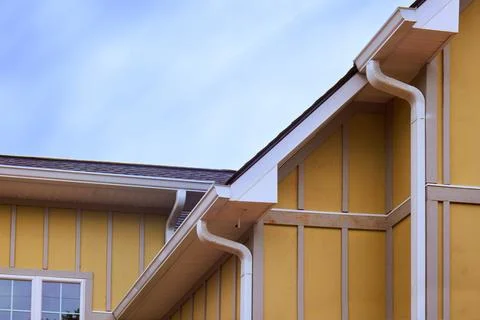 Yellow house structure with rooflines gutter details in clear sky Fotos de archivo