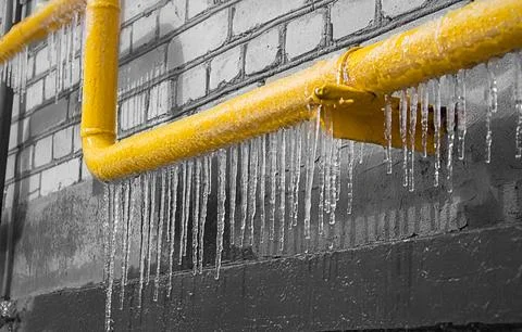 A yellow icy pipe with gas on the background of a gray wall. Foto stock