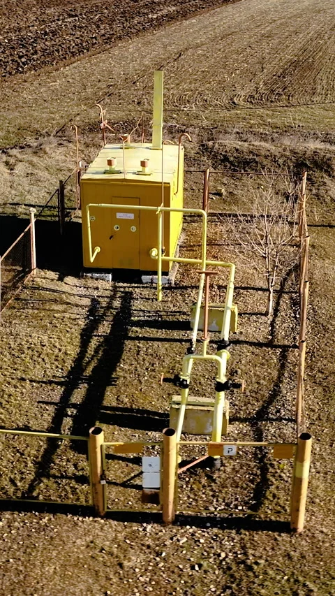 Yellow industrial control box with surrounding piping and fencing in a rural Video stock 336948402