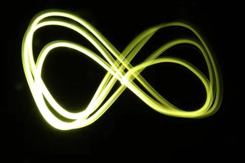 Yellow infinity loop light painting photography on a black background. Stock Photos
