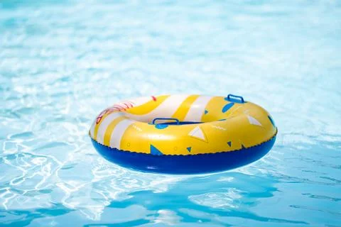 Yellow inflatable ring floating in a clear blue swimming pool, creating a b.. Photos