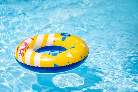 Yellow inflatable ring floating in a clear blue swimming pool, creating a b.. Photos