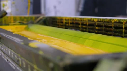 Yellow ink unit operating inside an offset industrial printing press Stock Footage 334776378