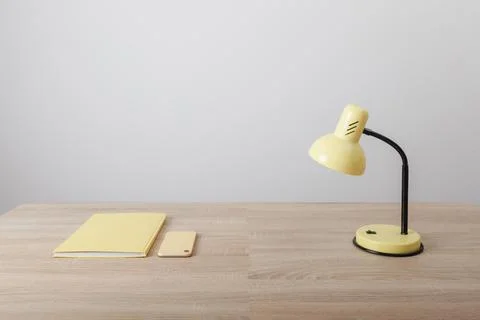 Yellow items notebook cup and lamp on wooden table Stock Photos