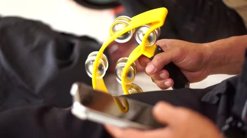 A yellow jingle ring percussion being played alongside a smartphone Video stock 344840328