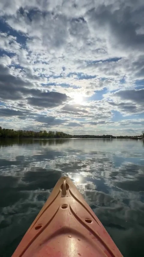 A yellow kayak floats in the reflection of clouds on a bright sunny day Video stock 335406027