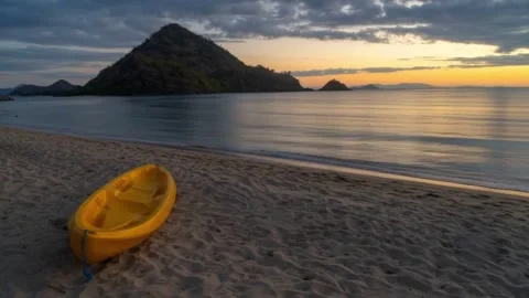 Yellow Kayak on a Sandy Beach at Sunset with Scenic Island Background Stock Footage 337942974