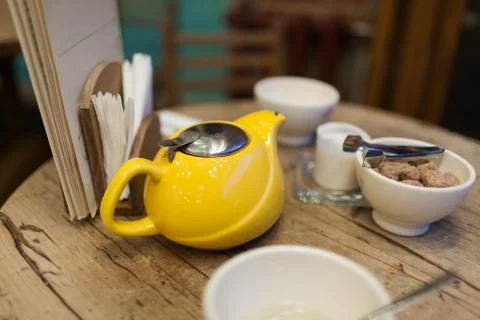 Yellow kettle with tea on the table in a caf next to a dish full of brown sug Stock Photos