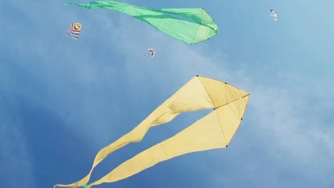 Yellow kite with two tails in flight against blue sky and sunny day Stock Footage 76265497