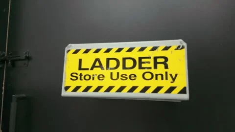 Yellow ladder store use only safety sign on dark door Stock Footage 332616744