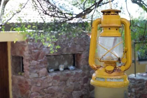 Yellow lantern hanging from a tree at the end of a house, next to an old ci.. Stock Photos