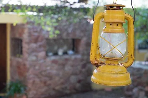 Yellow lantern hanging from a tree at the end of a house, next to an old ci.. Stock Photos