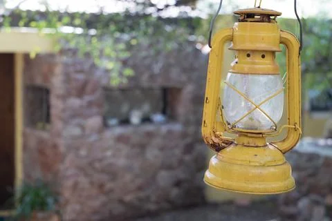 Yellow lantern hanging from a tree at the end of a house, next to an old ci.. Foto stock