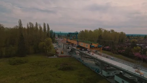 Yellow launching gantry constructing elevated transit guideway over highway Stock Footage 334509913