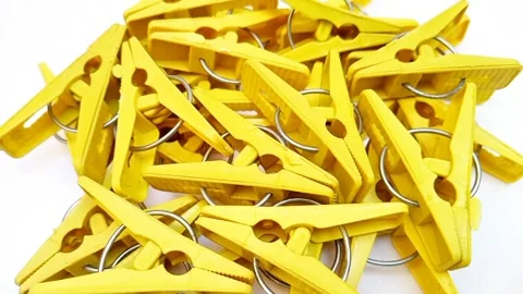 Yellow laundry clips rotating on the white background, plastic clothes pins.. Stock Footage 306200673