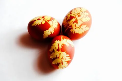 Yellow leafy patterns embellish these three red eggs. Stock Photos