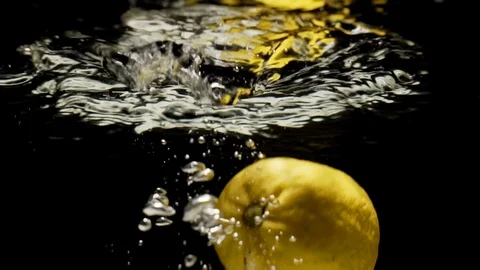 Yellow lemon falling into water Stock Footage 90386335