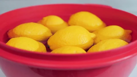Yellow lemons standing in the kitchen in a water-filled red plastic tub Stock-Footage 131017714