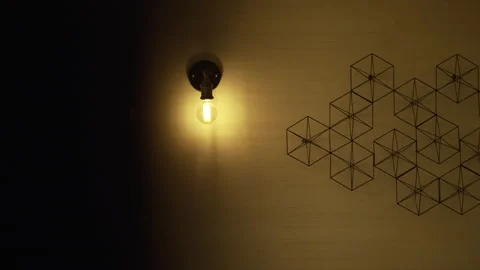 A yellow light bulb illuminates a room wall decorated with geometric pattern Stock Footage 221733519