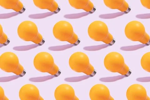 Yellow light bulb pattern isolated on light purple background Stock Photos