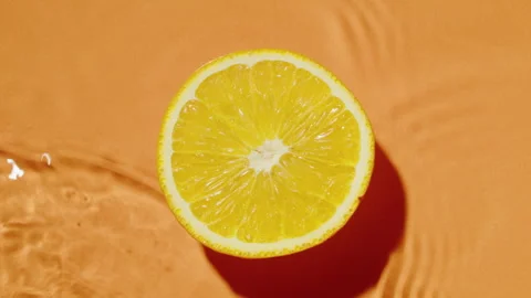 Yellow lime cut on orange background. Waves wash the fruit. Tasty citrus Stock Footage 243670419