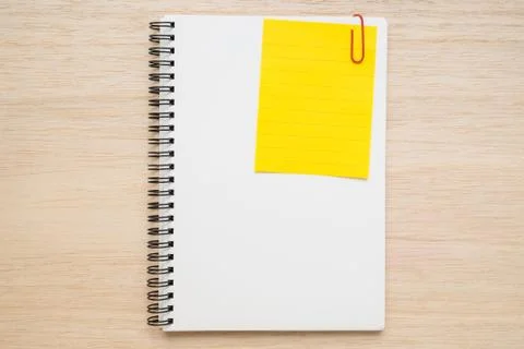 Yellow line memo note clipped on open spiral notebook on wooden background Stock Photos