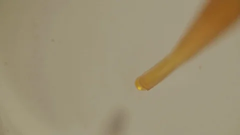 Yellow Liquid Dropping with Pipette into Container with Transparent Liquid Vídeos de archivo 111757365
