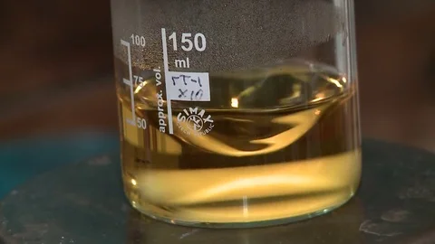 Yellow liquid rotates in a flask Stock Footage 72618024