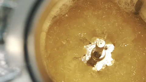 Yellow liquid in spinning machine pan from left to right close up slow motion Stock Footage 159055943