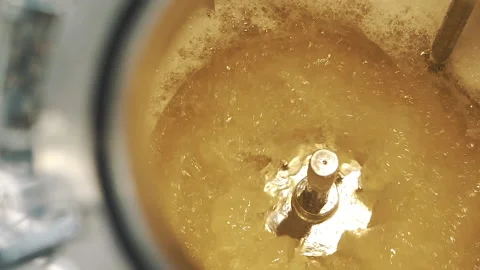Yellow liquid in spinning machine pan from right to left close up slow motion Stock-Footage 159059872
