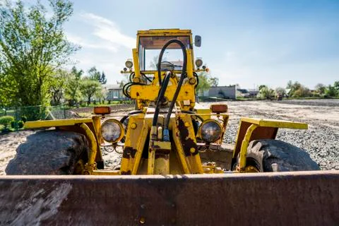 Yellow loader with empty bucket stands on a stone gravel during road Stock Photos
