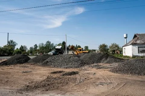 Yellow loader with empty bucket stands on a stone gravel during road Stock Photos