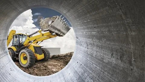 A yellow loader is seen digging and moving soil at a construction site. Cloud Stock Photos