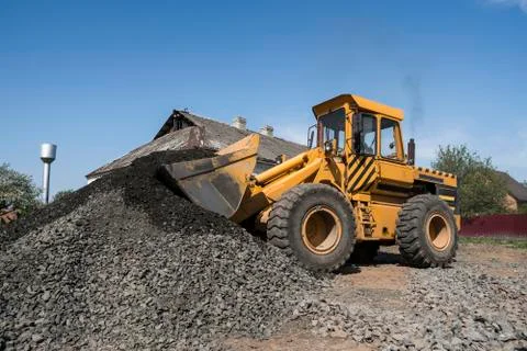 Yellow loader uploadind bucket with stone gravel during road construction works Stock Photos