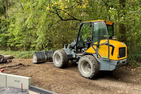 Yellow loader at work in a lush green construction site Stock Photos