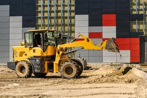A yellow loader is working at a construction site. The machine is moving di.. Stock Photos