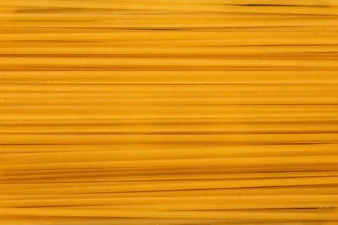 Yellow long spaghetti background, thin uncooked pasta arranged in rows, raw s 库存照片