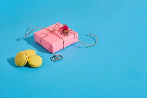 Yellow macarons with ring on a blue background. An offer of marriage, pink gift Fotos Stock