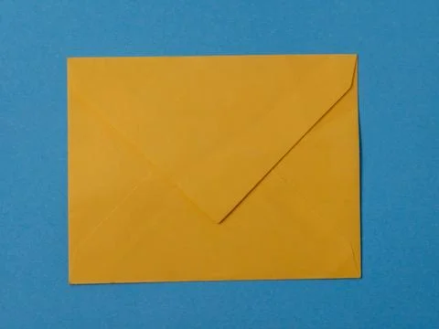 Yellow mail envelope flat lay on a solid blue background Foto stock