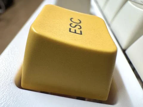 Yellow mechanical exit button on white mechanical keyboard for programmers and Stock Photos