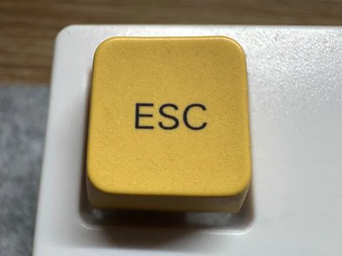 Yellow mechanical exit button on white mechanical keyboard for programmers and Stock Photos
