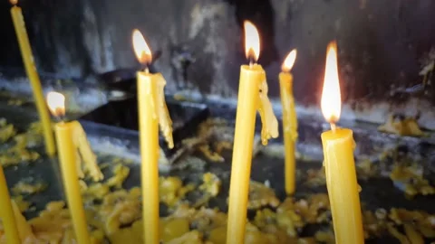 Yellow memory candles burning on a candlestick flooded with wax. Stock Footage 148139018