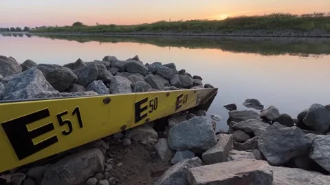 Yellow Metal Marker with E50 E51 Markings Beside Water Stock Footage 343340771