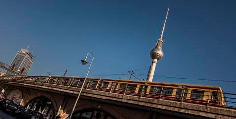 Yellow metro train passes over the bridge with a view of the TV tower. Stock Photos