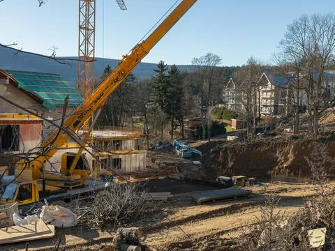 A yellow mobile crane works at an active residential construction site Stock Photos